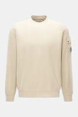 C.P. Company Sweatshirt sand, frontal aus leicht erhöhter Perspektive, Inside-Out-Design, reine Baumwolle, Ärmel-Tasche mit Linsen-Detail, Rundhals, Rippbündchen.