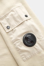 Nahaufnahme eines sandfarbenen C.P. Company Sweatshirts mit Inside-Out-Design, Fokus auf Ärmeltasche mit Linsen-Detail aus reiner Baumwolle.