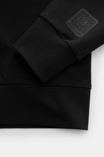Nahaufnahme des schwarzen C.P. Company Sweatshirts aus elastischem Baumwoll-Stretch-Fleece, Fokus auf Rippbündchen und Logo.