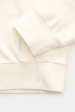 Nahe Aufnahme der Ärmelbündchen des 04651/ A trip in a bag Sweat-Troyer 'IF' offwhite, Sweat aus reiner Baumwolle, elastisch, weicher Griff, garment dyed, Regular Fit, mit kleinem Weblabel, flexiblen Rippbündchen und softer Innenseite.