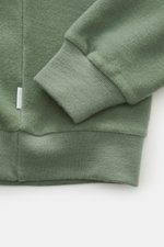 Nahaufnahme des graugrünen 04651/ A trip in a bag Rundhals-Sweatshirts im inside-Out Design, Fokus auf elastisches Bündchen und weichen Jersey aus Wolle und Baumwolle, Slim Fit, Perspektive von oben.