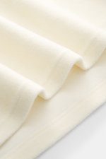 Nahaufnahme des cremefarbenen Stoffes des 04651/ A trip in a bag Troyer 'CW Zip Polo' creme, Mix aus Wolle und Baumwolle, weicher Griff, Regular Fit, klassischer Troyer-Kragen, innenliegende Brusttasche, kleines Weblabel in der Seitennaht.