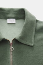 Nahaufnahme aus schräger Frontalperspektive des salbei-farbenen 04651/ A trip in a bag Troyer 'CW Zip Polo' mit klassischem Troyer-Kragen, Reißverschluss, weichem Griff, Regular Fit, innenliegender Brusttasche, kleinem Weblabel, Mix aus Wolle und Baumwoll