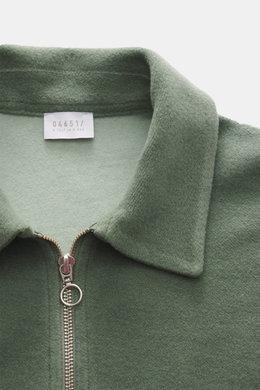 Nahaufnahme aus schräger Frontalperspektive des salbei-farbenen 04651/ A trip in a bag Troyer 'CW Zip Polo' mit klassischem Troyer-Kragen, Reißverschluss, weichem Griff, Regular Fit, innenliegender Brusttasche, kleinem Weblabel, Mix aus Wolle und Baumwoll