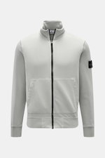 Stone Island Sweatjacke hellgrau, frontal fotografiert, aus softer Baumwolle, mit Reißverschluss, Stehkragen, Kängurutasche, Kompass-Badge.