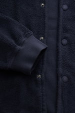 Nahaufnahme des 04651/ A trip in a bag Fleece-Blouson navy von vorne, Slim Fit, reine Baumwolle, weicher Griff, Druckknopfleiste, Blousonkragen, schräge Hüfttaschen, Rippbündchen, Weblabel.
