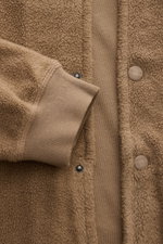 Nahaufnahme aus schräger Perspektive des 04651/ A trip in a bag Fleece-Blouson taupe mit Fleece aus reiner Baumwolle, weichem Griff, Slim Fit, Druckknopfleiste, Blousonkragen aus Rippstrick, schrägen Hüfttaschen, Rippbündchen und Weblabel in der Seitennah