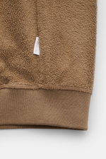 Nahaufnahme des unteren Bereichs des 04651/ A trip in a bag Fleece-Blouson taupe mit weichem Fleece aus reiner Baumwolle, komfortablem Rippbündchen und Weblabel in der Seitennaht.