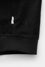 Close-up from the front bottom of 04651/ A trip in a bag Fleece blouson black showing pure cotton fleece, soft feel, slim fit, snap button placket, signature blouson collar in rib knit, angled hip pockets, comfortable ribbed bands, and woven label in the 