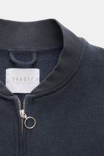 Close-up front view of the collar and zipper of the 04651/ A trip in a bag Sweat jacket 'CL Bomber' navy, featuring a garment-dyed organic cotton and linen blend, soft feel, regular fit, robust two-way zip with a ring pull, signature blouson collar, and f
