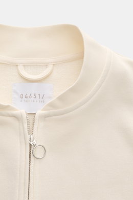 Close-up front view of 04651/ A trip in a bag Sweatjacke 'CL Bomber' creme with garment-dyed fabric, round zipper pull, and ribbed collar.

<p>Entspannt unterwegs: Die Sweatjacke 'CL Bomber' von 04651/ A TRIP IN A BAG kombiniert einen hochwertigen Mix aus