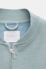 Close-up front view of 04651/ A trip in a bag Sweatjacke 'CL Bomber' rauchblau showing the garment-dyed fabric, robust two-way zipper with ring pull, and typical blouson collar.

<p>Entspannt unterwegs: Die Sweatjacke 'CL Bomber' von 04651/ A TRIP IN A BA
