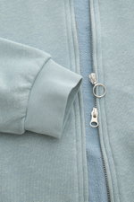 Close-up front view of 04651/ A trip in a bag Sweatjacke 'CL Bomber' rauchblau showing garment-dyed fabric, robust two-way zipper with ring pull, and ribbed cuff.

<p>Entspannt unterwegs: Die Sweatjacke 'CL Bomber' von 04651/ A TRIP IN A BAG kombiniert ei