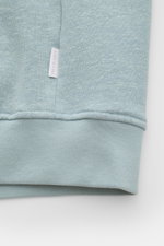 Close-up view of the cuff and small web label of the 04651/ A trip in a bag Sweatjacke 'CL Bomber' rauchblau, made from a soft mix of organic cotton and linen with a garment-dyed finish, featuring flexible ribbed cuffs for comfort. <p>Entspannt unterwegs: