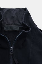 Nahaufnahme der Stone Island Sweatjacke 'Ghost Piece' navy mit Stehkragen, Reißverschluss und tonalem Kompass-Badge aus elastischer Baumwolle, soft und garment dyed.
