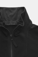 Nahaufnahme der Stone Island Sweatjacke 'Ghost Piece' schwarz mit Stehkragen, Reißverschluss und tonalem Kompass-Badge, von vorne fotografiert.