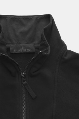 Nahaufnahme der Stone Island Sweatjacke 'Ghost Piece' schwarz mit Stehkragen, Reißverschluss und tonalem Kompass-Badge, von vorne fotografiert.