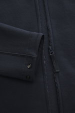 Nahaufnahme der Stone Island Sweatjacke 'Ghost Piece' navy mit Umlegekragen, Reißverschluss und tonalem Kompass-Badge aus Wolle-Baumwoll-Mix, weicher Innenseite, regulierbaren Ärmelbündchen, fotografiert von oben frontal.