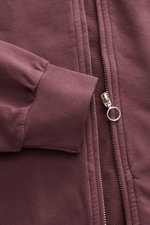 Nahaufnahme der bordeauxfarbenen 04651/ A trip in a bag Sweatjacke 'IF Track' mit Reißverschluss, hochschließendem Kragen und elastischem Rippbündchen aus super softem Baumwoll-Jersey, fotografiert von oben.
