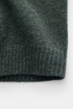 Nahaufnahme des grob gestrickten, dunkelgrün melierten 04651/ A trip in a bag Cardigan 'Hunter' aus Merinowolle-Microfaser-Mix mit softem Griff, Rippbündchen, V-Ausschnitt, Vier-Knopf-Leiste, Regular Fit und aufgesetzten Fronttaschen, fotografiert von vor