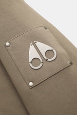 Close-up side view of the Moose Knuckles Sweat jacket 'Classic Bunny' taupe showing the metal logo patch on soft cotton microfiber fabric.

<p>Perfect for cold days: With lightweight padding and a hood with detachable faux fur lining, you will be well-equ