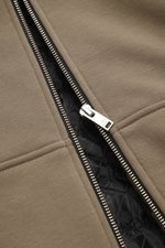 Nahaufnahme aus schräger Perspektive der robusten Reißverschlussleiste der taupefarbenen Moose Knuckles Sweatjacke 'Classic Bunny' mit leichter Wattierung und geprägtem Innenfutter.