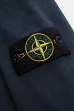 Stone Island Kapuzenpullover navy im Close-up, Sweat aus reiner Baumwolle, weicher Griff, garment dyed, Regular Fit, markante Overlock-Nähte, Kapuze mit Tunnelzug, Kompass-Badge am Ärmel, Kängurutasche, Rippbündchen.