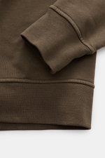 Nahaufnahme des Stone Island Kapuzenpullover dark olive in Regular Fit, fokussiert auf Rippbündchen und Overlock-Nähte aus weicher Baumwolle.