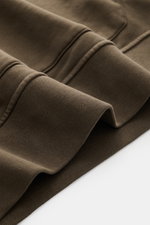 Nahaufnahme des Stone Island Kapuzenpullover dark olive in Regular Fit, Fokus auf Rippbündchen und markante Overlock-Nähte, weicher Baumwollstoff.