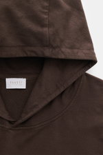 Detailaufnahme aus Frontperspektive des dunkelbraunen 04651/ A trip in a bag Kapuzenpullover 'IF Hoodie' aus reiner Baumwolle, elastisch, sehr weich, Regular Fit mit praktischer Kapuze, kleinem Weblabel in der Seitennaht und komfortablen Rippbündchen.