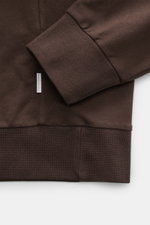 Nahaufnahme des Ärmelbündchens und Saums vom 04651/ A trip in a bag Kapuzenpullover 'IF Hoodie' dunkelbraun, reine Baumwolle, elastisch, sehr weich, Regular Fit, Kapuze, Weblabel an Seitennaht, komfortable Rippbündchen.