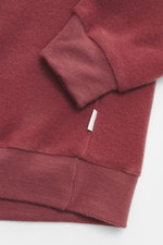 Detailaufnahme von Ärmel und Saum des rotbraunen 04651/ A trip in a bag Kapuzenpullover 'CW Hoodie' aus Wolle und Baumwolle, weicher Griff, Regular Fit, praktische Kapuze, kleines Weblabel in der Seitennaht, komfortable Rippbündchen.