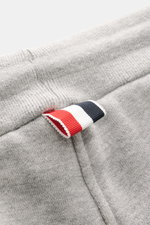 Nahaufnahme der grau melierten Thom Browne Sweathose mit elastischem Bund und markentypischem Streifen-Detail, weicher Baumwollstoff.