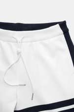 Nahaufnahme der Thom Browne Sweathose weiß/navy von oben, zeigt elastischen Bund mit Tunnelzug, weichen Baumwollstoff, markentypisches Streifen-Detail und versteckte Hüfttaschen.
