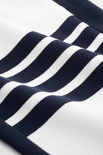 Nahaufnahme der Thom Browne Sweathose weiß/navy aus reiner Baumwolle, Detailfoto der markentypischen navy-weißen Streifen, seitliche Perspektive.