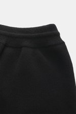 Close-up front view of Ami Paris Merino jogpants black, showing high elastic waistband with drawstring, pure merino wool, soft touch, loose fit, leather logo detail, comfortable ribbed cuffs, and side pockets.