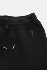 Close-up front view of Ami Paris Merino jogpants black, showing pure merino wool fabric with a soft touch, loose fit, high elastic waistband with drawstring, leather logo detail, comfortable ribbed cuffs, and side pockets.