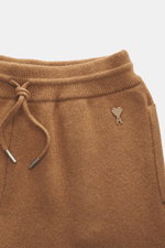 Close-up front view of Ami Paris Merino jogpants light brown showing pure merino wool fabric, soft touch, loose fit, high elastic waistband with drawstring, leather logo detail, ribbed cuffs, and side pockets.