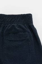 Close-up rear view of 04651/ A trip in a bag 'Terry' shorts navy, showcasing elastic waistband, back hip pocket, and soft terrycloth texture.

<p>With the model 'Terry' 04651/ A TRIP IN A BAG presents a comfortable pair of shorts in wonderfully soft terry