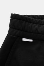 Nahaufnahme der elastischen Bundkante der 04651/ A trip in a bag Sweatshorts 'Studio' schwarz, Sweat aus reiner Baumwolle, schwere Qualität, weicher Griff, Slim Fit, Tunnelzug, angedeuteter Eingriff, französische Taschen, Leistentasche am Gesäß, kleines W