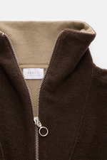 Close-up front view of the 04651/ A trip in a bag Troyer 'Cw Quarter Zip' dunkelbraun, showing its soft fleece texture, wool-cotton mix, doubleface quality with jersey inner side, regular fit, zippered Troyer collar, ribbed cuffs, and side seam web label.