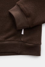 Close-up image of the sleeve and waistband of the 04651/ A trip in a bag Troyer 'Cw Quarter Zip' dunkelbraun, showing its soft fleece texture and ribbed cuffs from a top-down perspective. Lässig durch die Übergangszeit: Der Troyer von 04651/ A TRIP IN A B