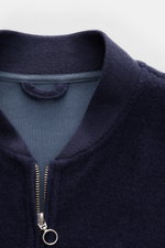 Close-up front view of 04651/ A trip in a bag Blouson dunkelblau with ribbed collar, two-way zipper, and soft wool-cotton fleece texture. Lässig durch die Übergangszeit: Der Blouson von 04651/ A TRIP IN A BAG überzeugt mit seiner samtigen Fleece-Textur au