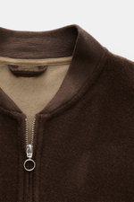 Close-up front view of 04651/ A trip in a bag Blouson dunkelbraun showing its soft, dark brown fleece texture, ribbed collar, and silver two-way zipper ring pull. Lässig durch die Übergangszeit: Der Blouson von 04651/ A TRIP IN A BAG überzeugt mit seiner 