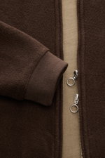 Close-up front view of the 04651/ A trip in a bag Blouson dunkelbraun, showcasing its dark brown soft fleece texture, ribbed cuff, and two-way silver zipper. Lässig durch die Übergangszeit: Der Blouson von 04651/ A TRIP IN A BAG überzeugt mit seiner samti