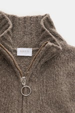 Nahaufnahme von 04651/ A trip in a bag Troyer 'Grainy' taupe, von oben fotografiert, Boucléstrick mit mittelfeinem Strickbild, Mix aus Wolle und Microfaser, weicher Griff, Regular Fit, hoher Rippstrickkragen mit Zipper und breiten Rippbündchen.