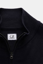 Nahaufnahme des C.P. Company Troyer navy aus weicher Schurwolle mit Troyer-Kragen, Reißverschluss und labeltypischem Linsen-Detail.