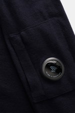 Nahaufnahme des C.P. Company Troyer navy aus weicher Schurwolle, mit Taschennaht und labeltypischem Linsen-Detail sichtbar.