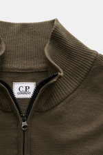Nahaufnahme des olivfarbenen C.P. Company Troyer aus weicher Schurwolle mit Troyer-Kragen, Reißverschluss und labeltypischem Linsen-Detail.