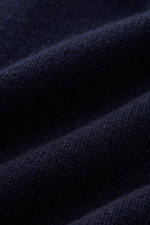 Close-up front view of navy blue knit fabric texture of Stone Island Half-zip jumper 'Lambswool' navy, a warm wool blend with embossed collar buttons.